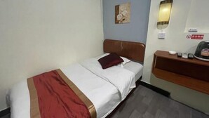 Ein Hotelzimmer mit Bett, Nachttisch, Wandlampe, einem Gemälde und einem Schild.