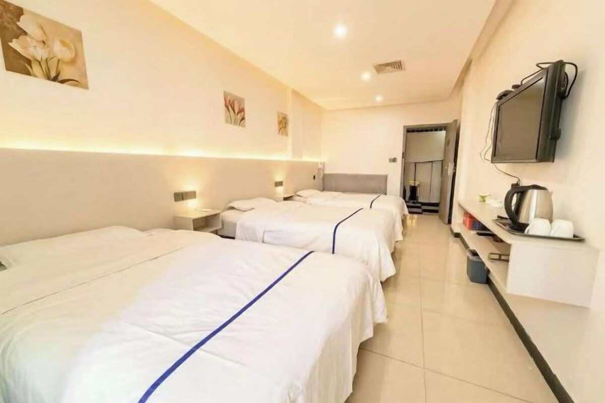 Habitación de hotel con dos camas, televisión y una kitchenette.