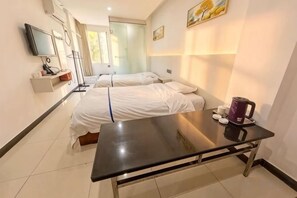 A hotel room with two beds, a flat-screen TV, a coffee machine, and a table.