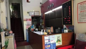 Un comptoir d’accueil doté d’un écran numérique, un escalier et une chaise rouge.