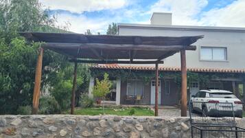 A house with a stone wall, a covered patio, and a parked car.