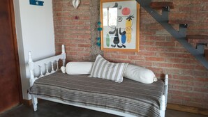 Un dormitorio con una cama, una pared de ladrillo, una escalera y una obra de arte enmarcada.