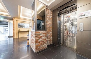 Un vestíbulo moderno con una pared de acento de ladrillo, un mostrador de recepción y un ascensor.