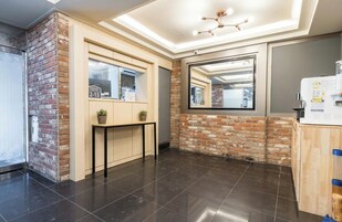 Un vestíbulo moderno con una pared de acento de ladrillo, un mostrador de recepción, un espejo grande y una lámpara en el techo.
