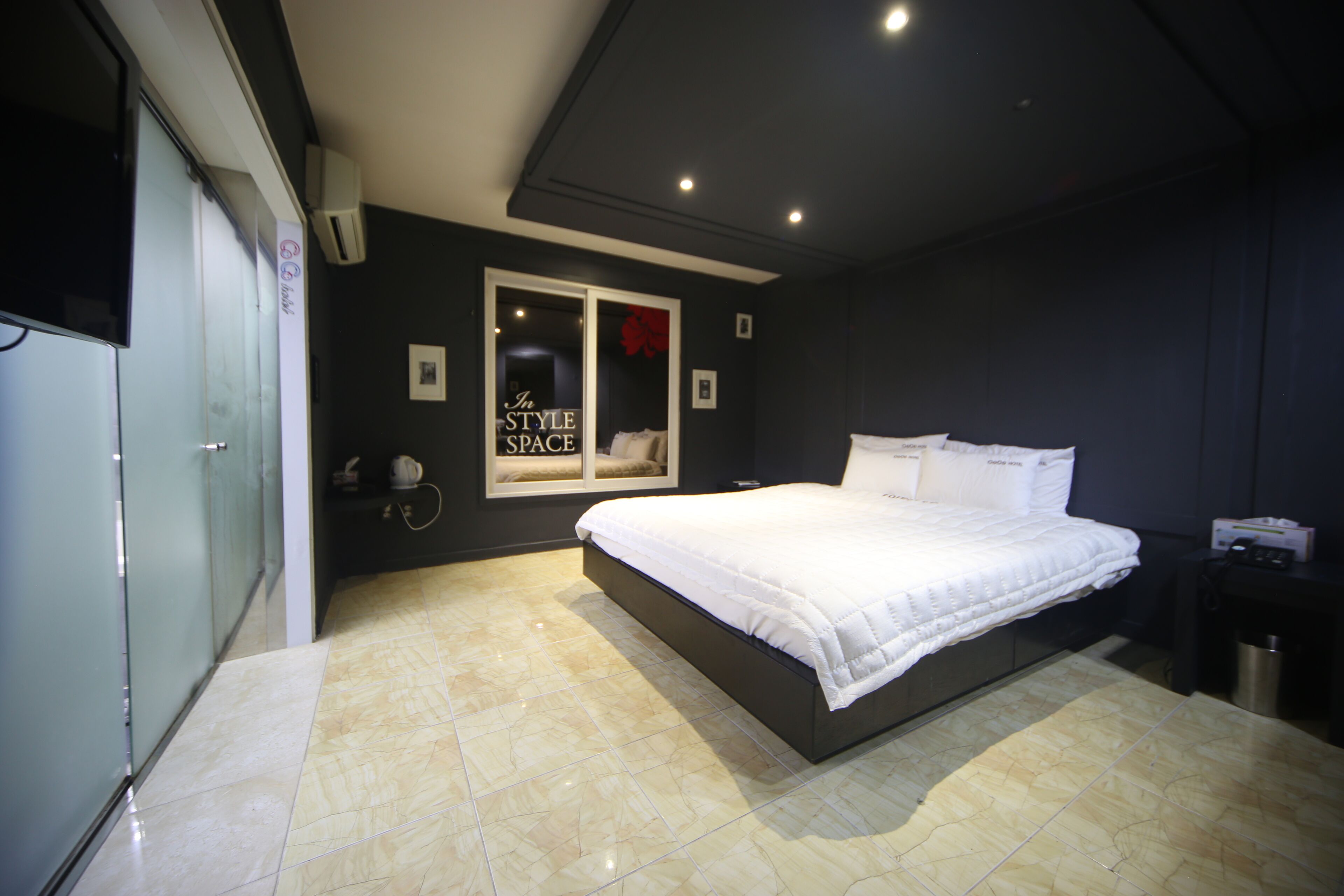 A modern bedroom with a large bed, a wardrobe, and a mirror.