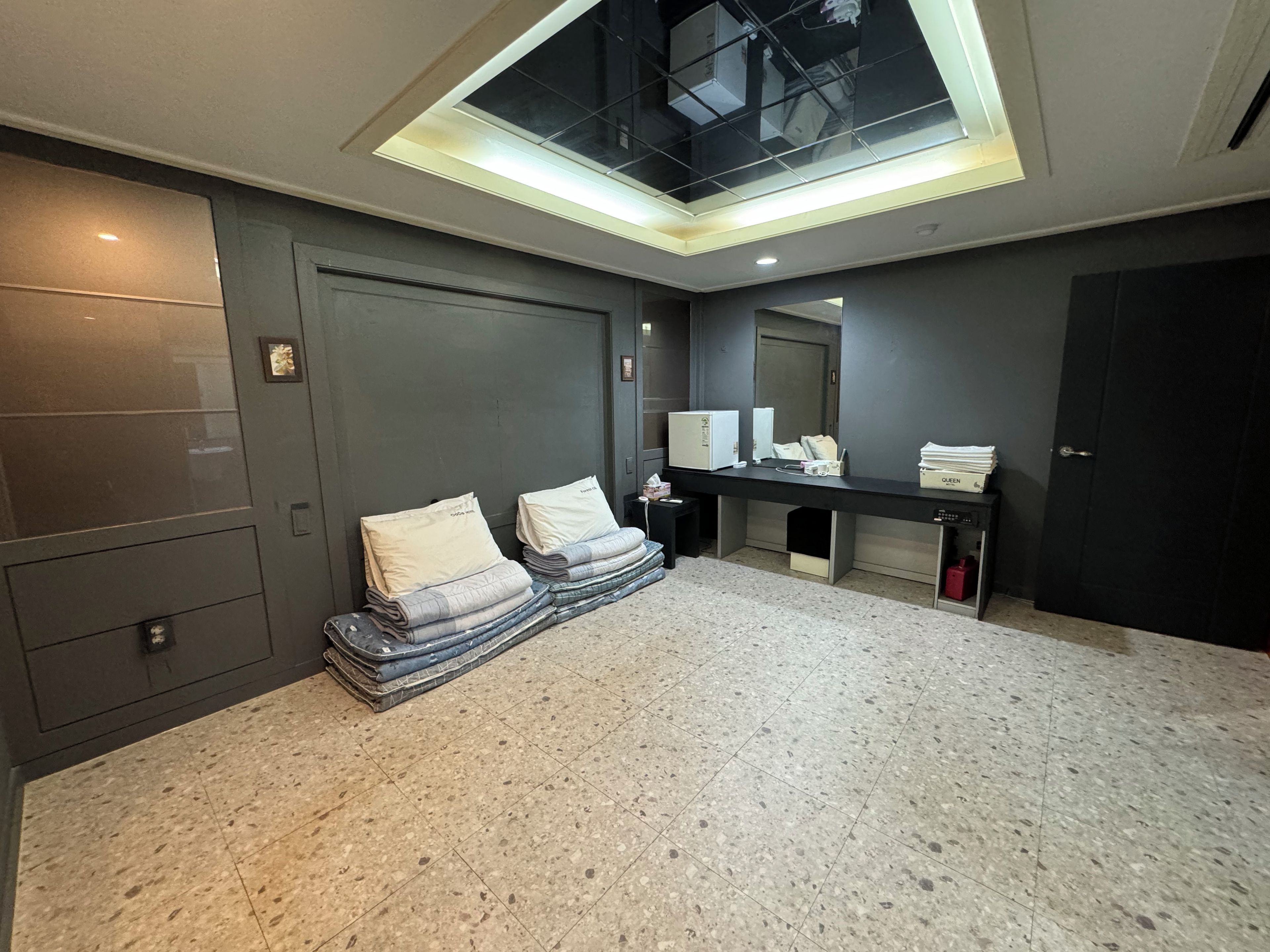 A hotel room with a large bed, a desk with a computer, and a skylight.