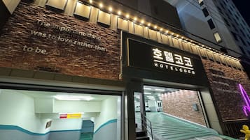 A hotel entrance with a brick facade, illuminated signage, and a staircase leading to the entrance.