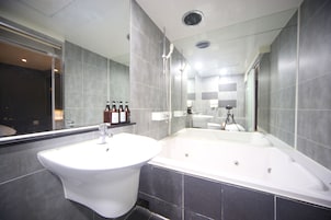Un baño moderno con un lavabo grande, una bañera y un espejo.