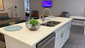 A modern kitchen with a white countertop, stainless steel sink, and a built-in dishwasher. - Disney-Area 4BR | Pool + Patio (Kissimmee)