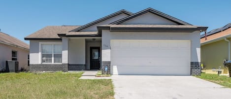 A single-story house with a garage, a front door, and a small front yard.