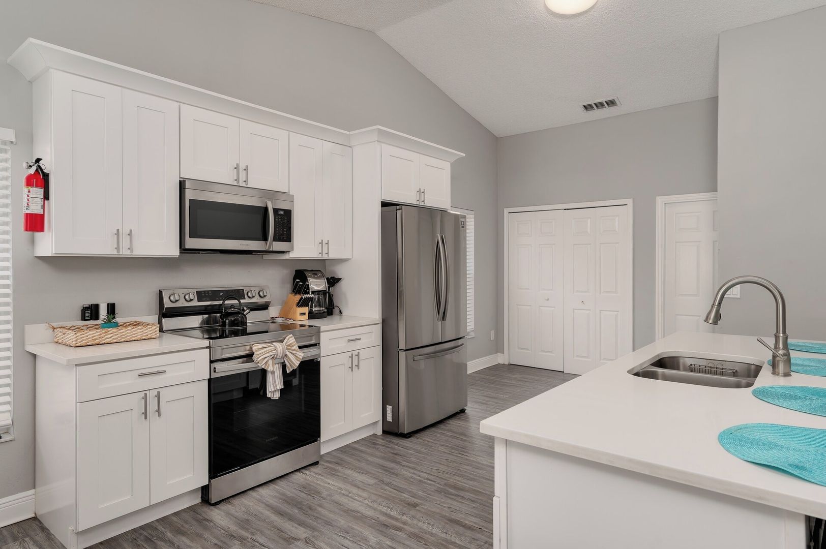 A modern kitchen with white cabinetry, stainless steel appliances, and a built-in oven.