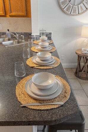 A kitchen counter with a set table for four, including plates, bowls, and cutlery.