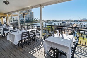An outdoor dining area with tables and chairs, overlooking a marina with boats and buildings in the background. - 500 feet to Beach : Snowbird Rates Nov 1 – Feb 28 (Destin)