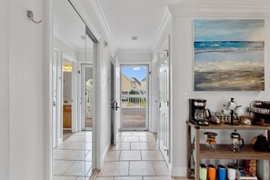 A hallway with white walls, a tiled floor, and a view to the outside. There is a shelf with kitchen items and a painting on the wall. - 500 feet to Beach : Snowbird Rates Nov 1 – Feb 28 (Destin)