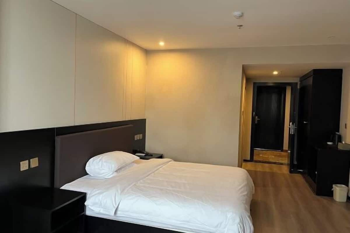 Une chambre d’hôtel avec un lit, une table de chevet et une armoire.