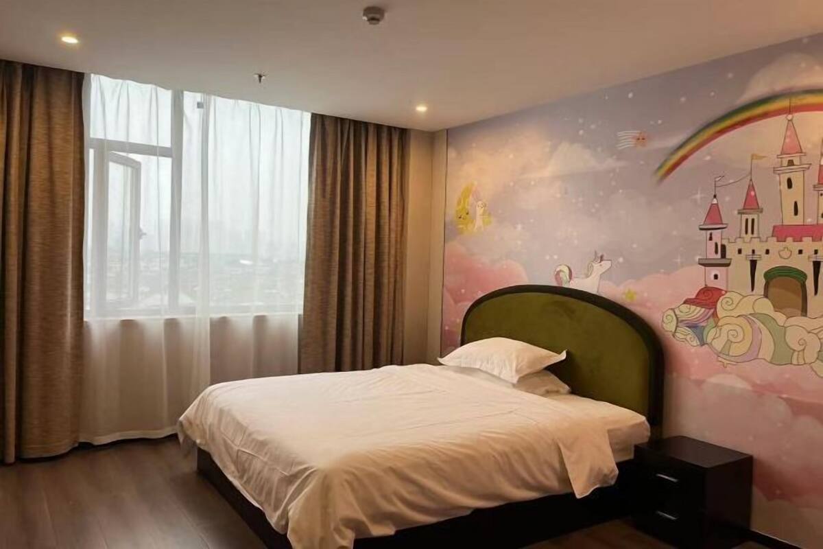 Une chambre d’hôtel avec un grand lit, une vue par la fenêtre et une fresque murale.