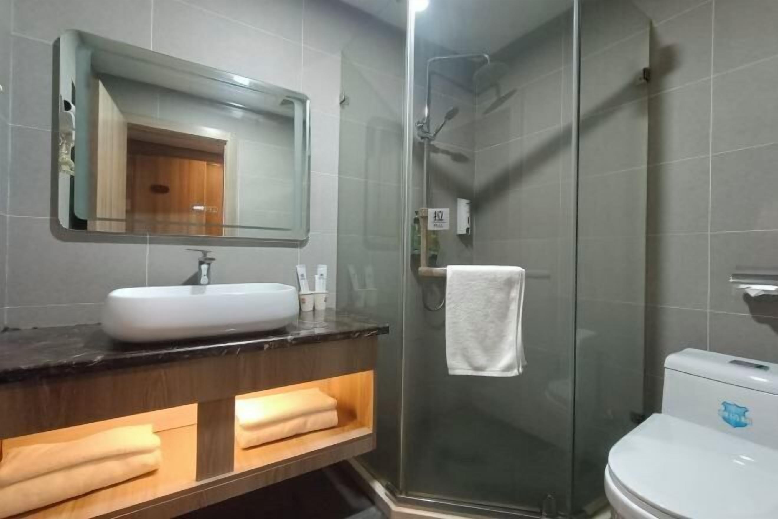 Un bagno moderno con doccia a schermo, un lavandino bianco e un water.
