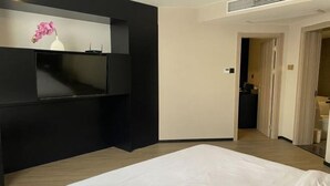 A hotel room with a bed, a TV on the wall, a small table, and a door leading to a bathroom. - Ketai Boutique Hotel (Shaoxing Keqiao Oriental Landscape Park) (Shaoxing)