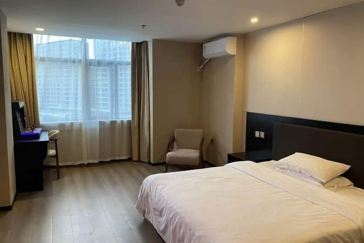 Une chambre d’hôtel avec un lit, un bureau, une chaise et une fenêtre avec des rideaux.