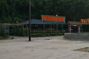 A hotel sign with a blue background and red lettering, a small structure with a roof, and a paved area in front. - Lingyun story Hotel (Lingyun)