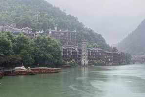 Une ville riveraine, avec des bâtiments qui bordent le cours d’eau, un pont et une personne à bord d’un bateau.