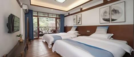 A hotel room with two beds, a TV, a desk, and a balcony with a view.