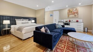 Un dormitorio moderno con cama, sofá, mesa de comedor y zona de cocina.