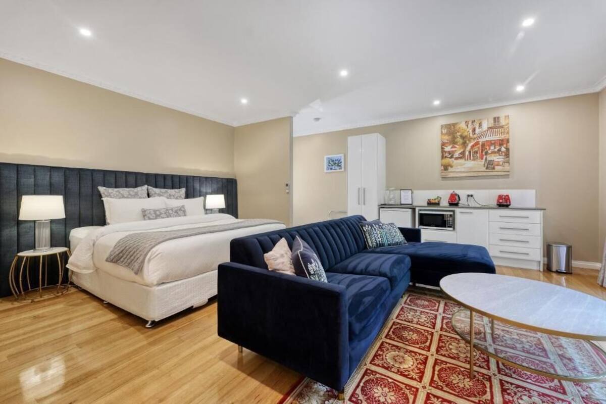 Een moderne slaapkamer met een bed, een bank, een eettafel en een keukenhoek.