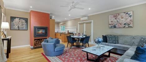 A living room with a fireplace, a sofa, a coffee table, and a dining area with chairs.