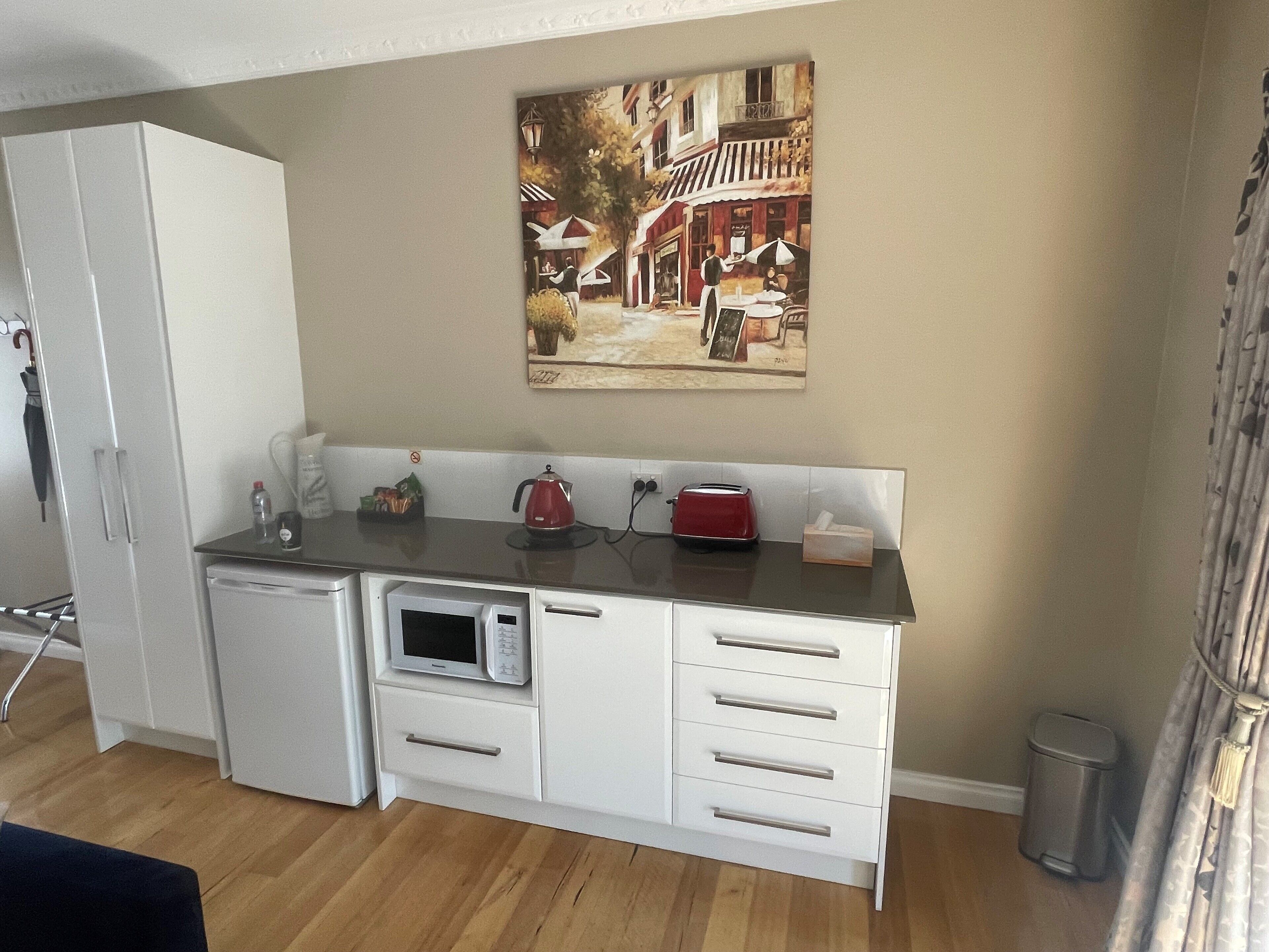 Eine kompakte Küchenzeile mit einer Mikrowelle, einem Wasserkocher und einem Toaster auf der Arbeitsfläche.
