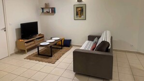 Ein Wohnzimmer mit Fernseher, einer Couch, einem Couchtisch und einem Deckenventilator.