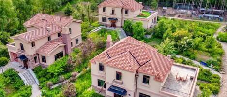 A residential complex with multiple houses, each featuring a distinct architectural style with red-tiled roofs and a central courtyard.