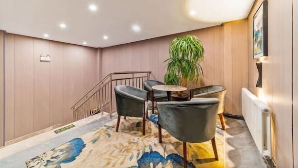 A modern hotel lobby with a staircase, a small seating area with chairs and a table, and a potted plant. - Homeinn Ease Hotel (Harbin Central Avenue Flood Control Memorial Tower) (Harbin)