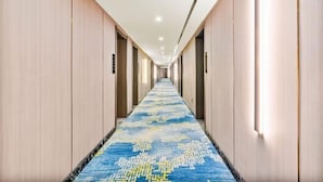A hotel hallway with a patterned carpet, wooden walls, and recessed lighting. - Homeinn Ease Hotel (Harbin Central Avenue Flood Control Memorial Tower) (Harbin)