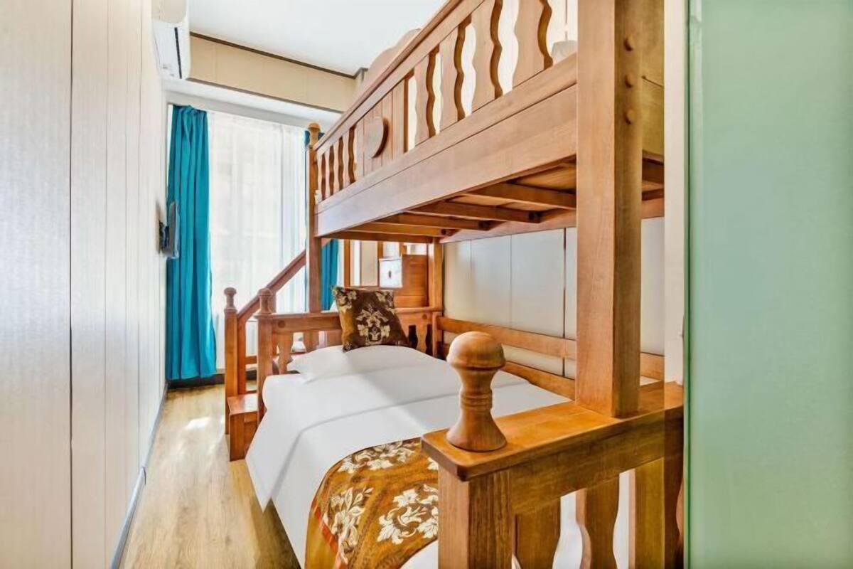 A bedroom with a wooden bed frame, a headboard, a bedside table, and a window with curtains.