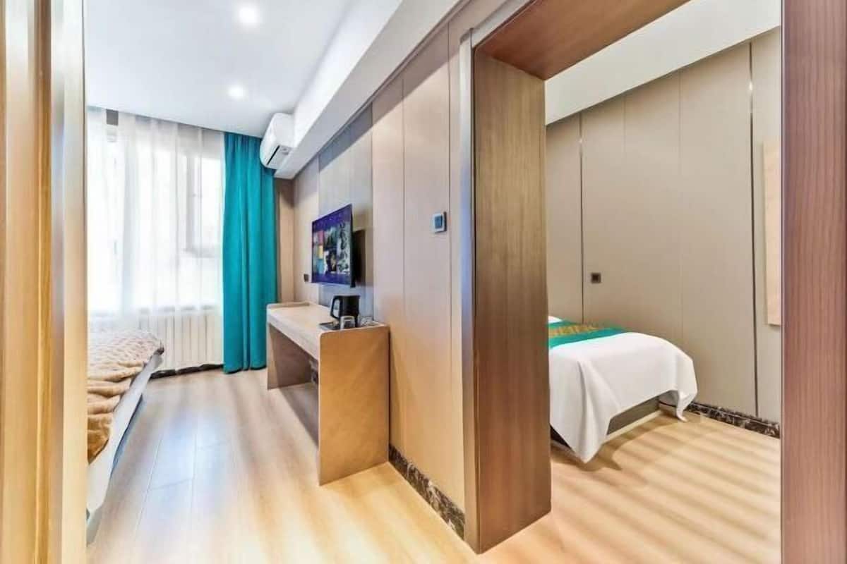 A hotel room with a bed, a desk, a TV, and a window with curtains.