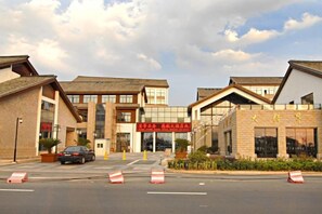 A building with a prominent entrance, multiple windows, and a clear sky. - Cihang Hotel (Zhoushan)
