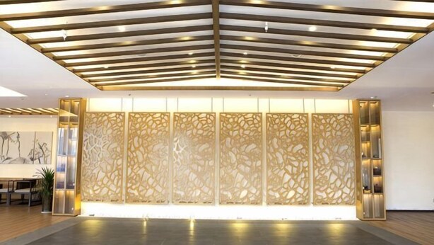 A reception area with a modern design, featuring a patterned wall and a ceiling with linear lighting. - Cihang Hotel (Zhoushan)