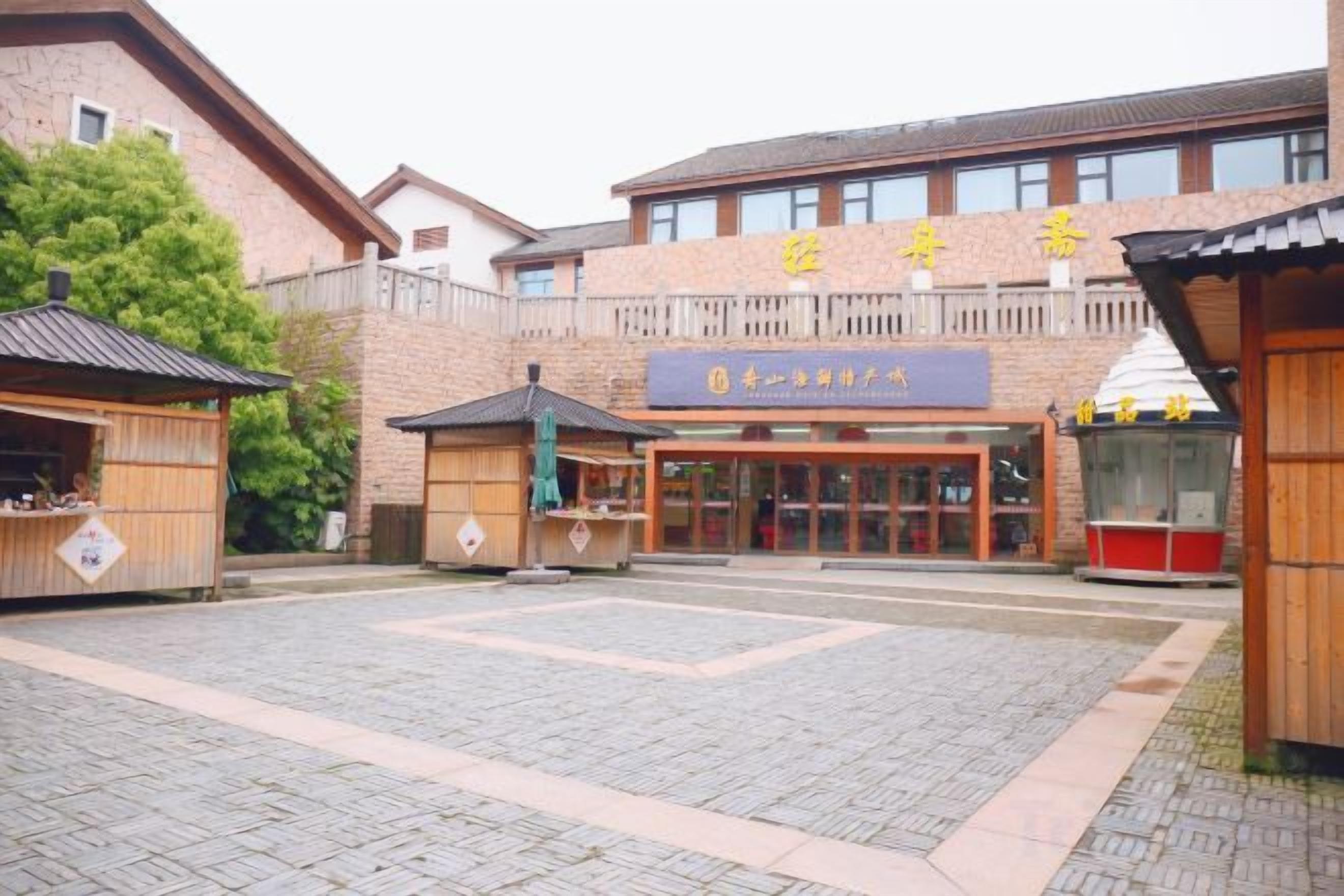 Entrada de hotel com galeria coberta, balcão de recepção e fachada de construção tradicional.