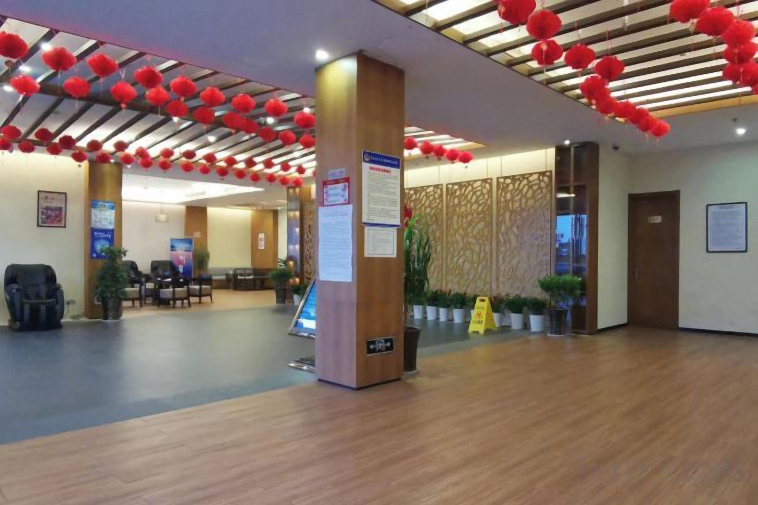 A hotel lobby with a reception desk, seating area, and decorative red lanterns on the ceiling.