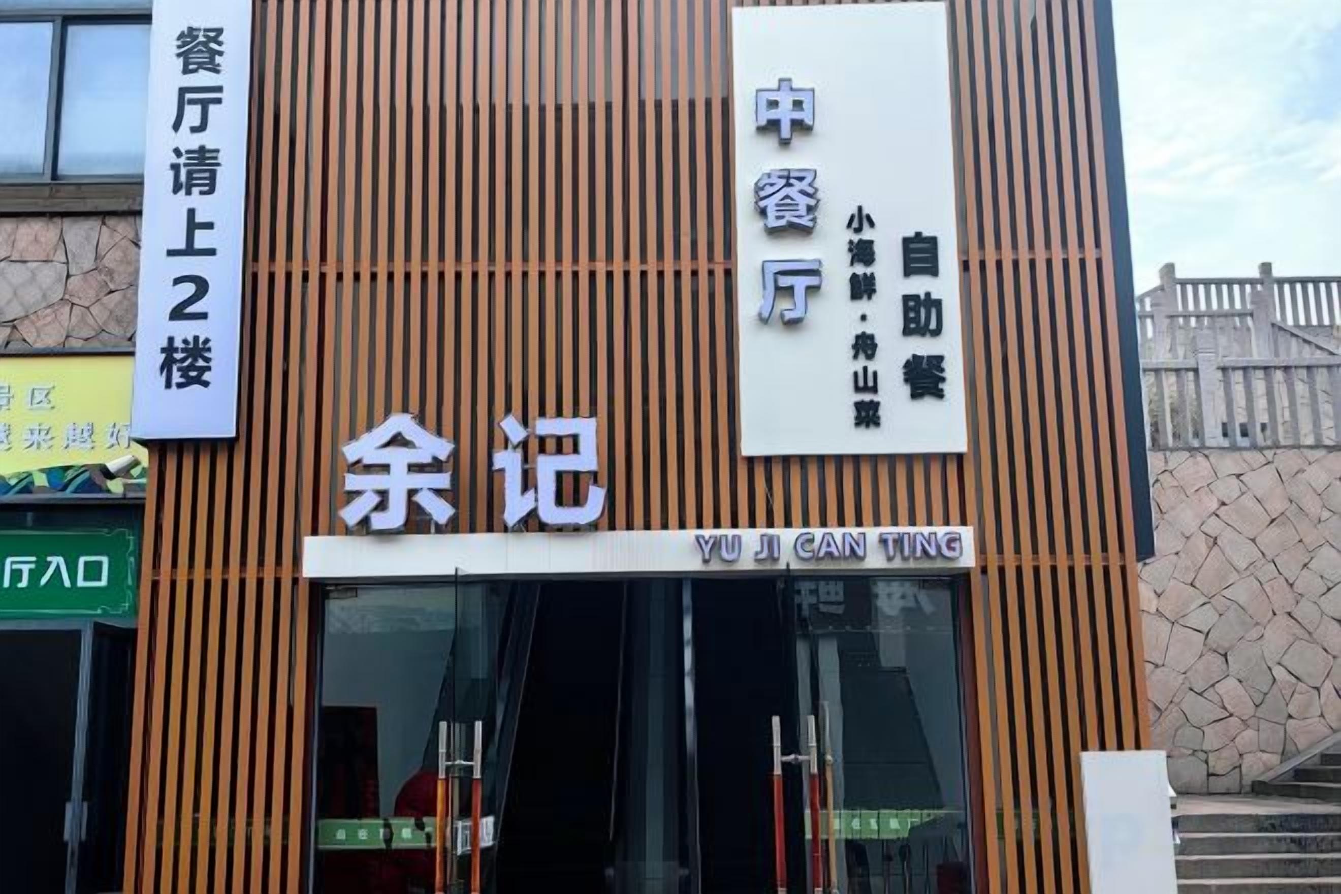 A building with vertical wooden slats, a sign with Chinese characters, and a visible entrance.