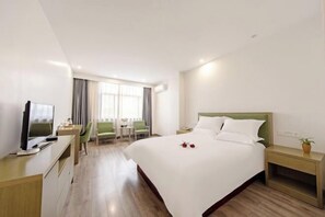 Una habitación de hotel con una cama, un escritorio, un televisor, una silla y una ventana.