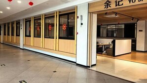 A modern hotel corridor with wooden paneling, a reception area, and a dining space. - Cihang Hotel (Zhoushan)