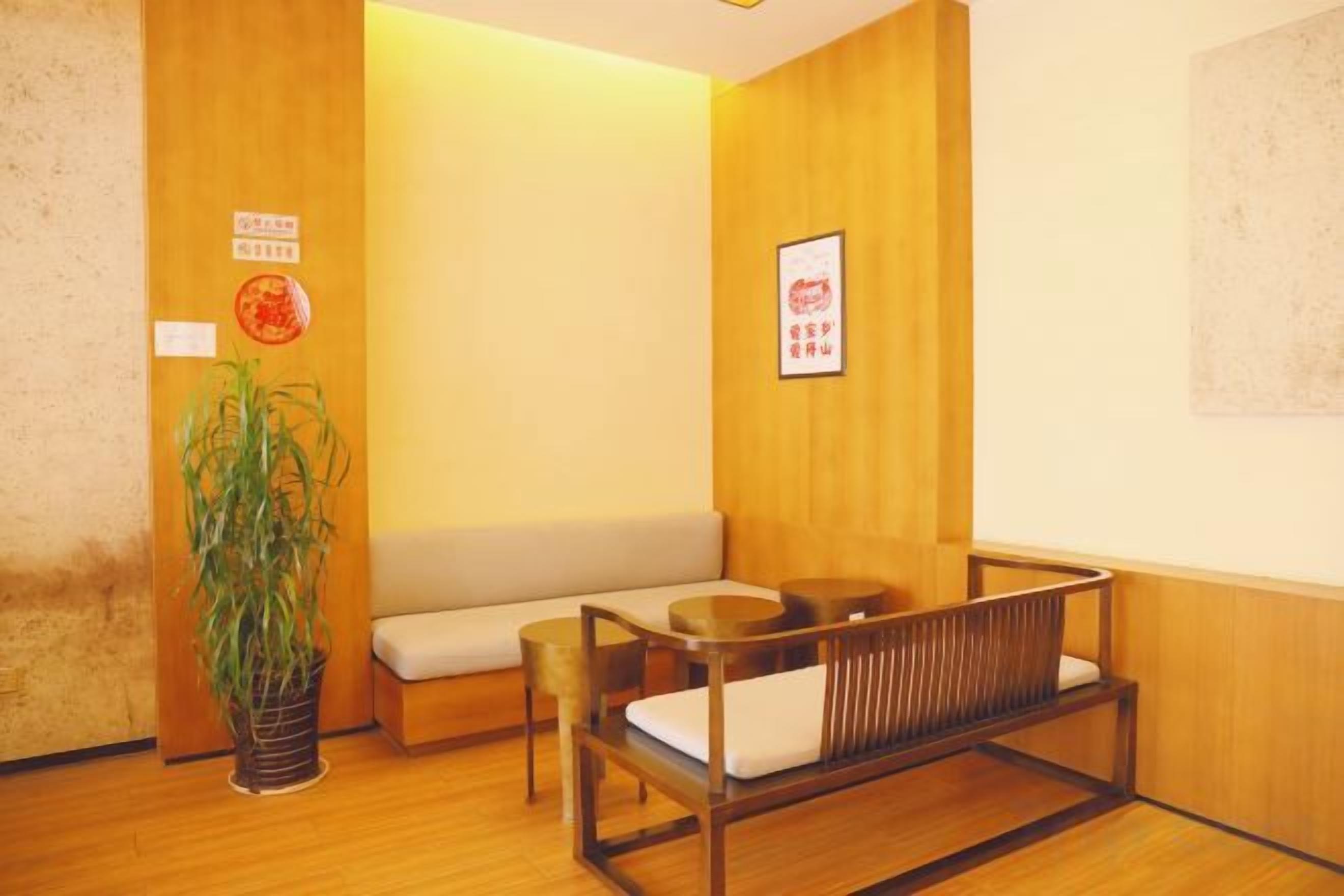 A room with a wooden floor, a sofa, a table, and a potted plant.