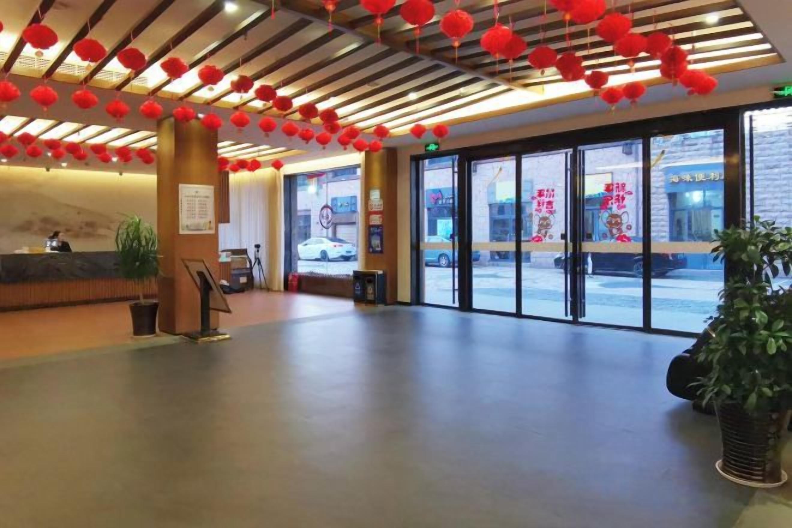 A hotel lobby with a reception desk, large windows, and red lanterns on the ceiling.