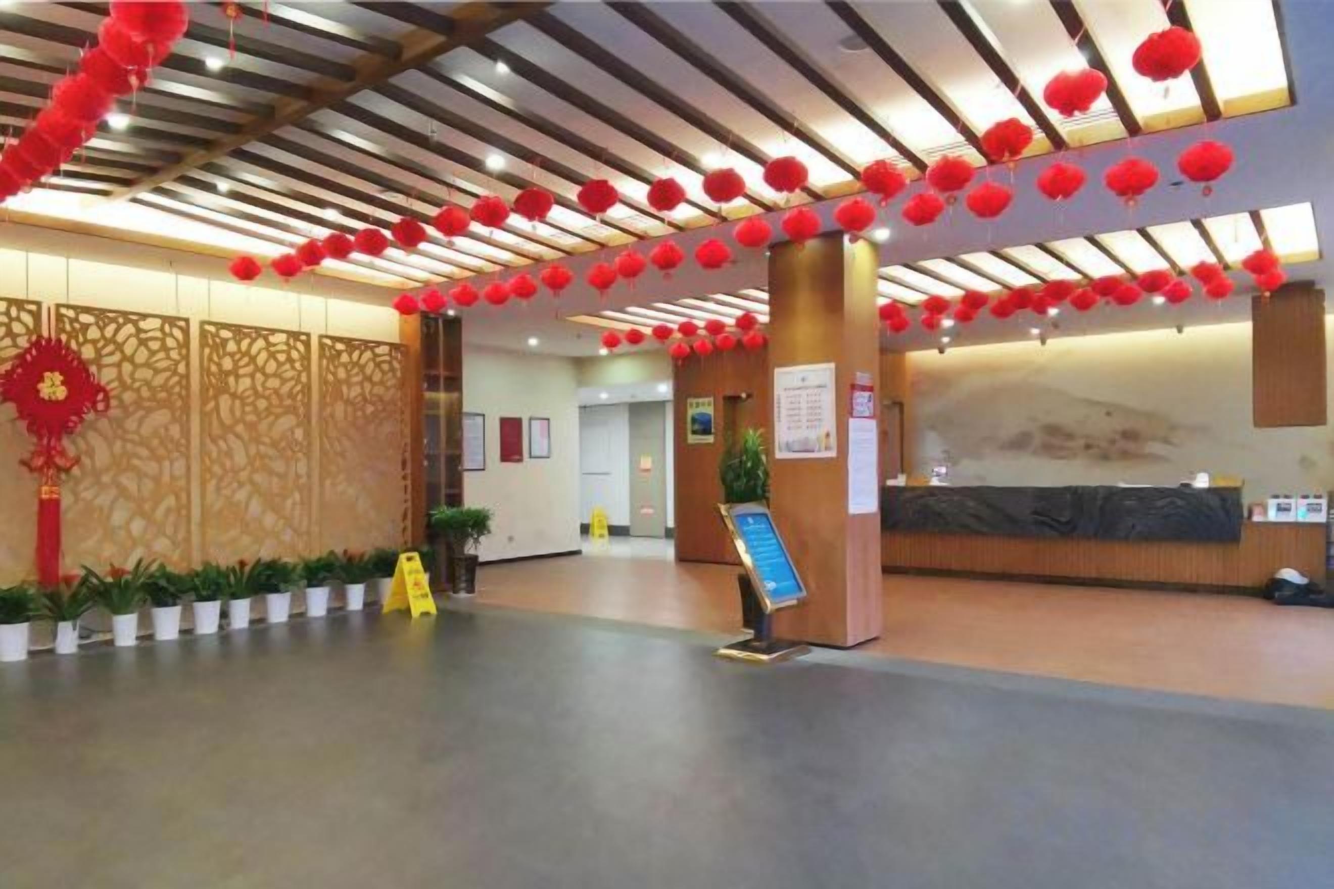 Un vestíbulo de hotel con una recepción, un amplio biombo decorativo y un plano de distribución.
