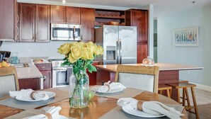 A modern kitchen with wooden cabinets, stainless steel appliances, and a dining area set for a meal.