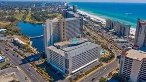 A high-rise hotel with multiple floors, a rooftop pool, and a view of the beach and ocean.