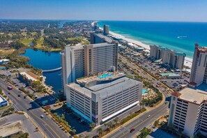 Un hotel de gran altura con varios pisos, una piscina en la azotea y vistas a la playa y al océano.