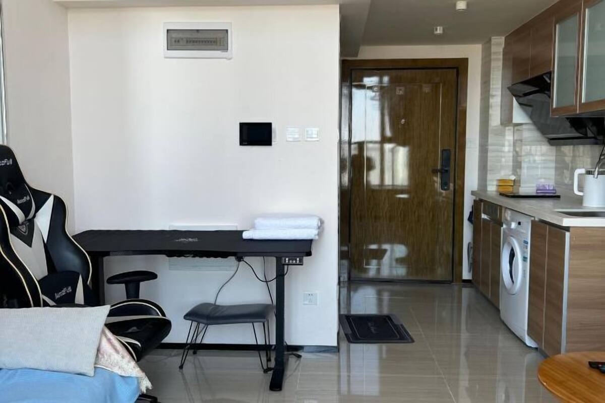 A modern kitchen with a washing machine, a dining area with a table and chairs, and a small office space with a desk and chair.